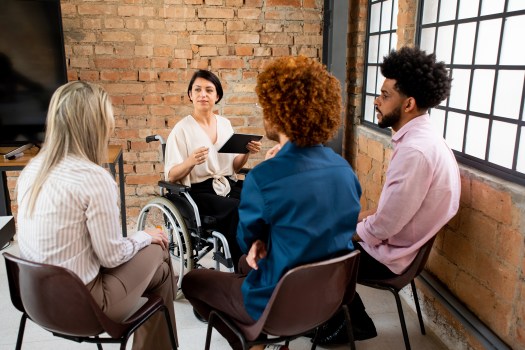 woman in wheelchair speaking to a small group of individuals